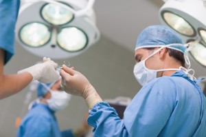 Doctor receiving a surgical scissor from a nurse in operating theater