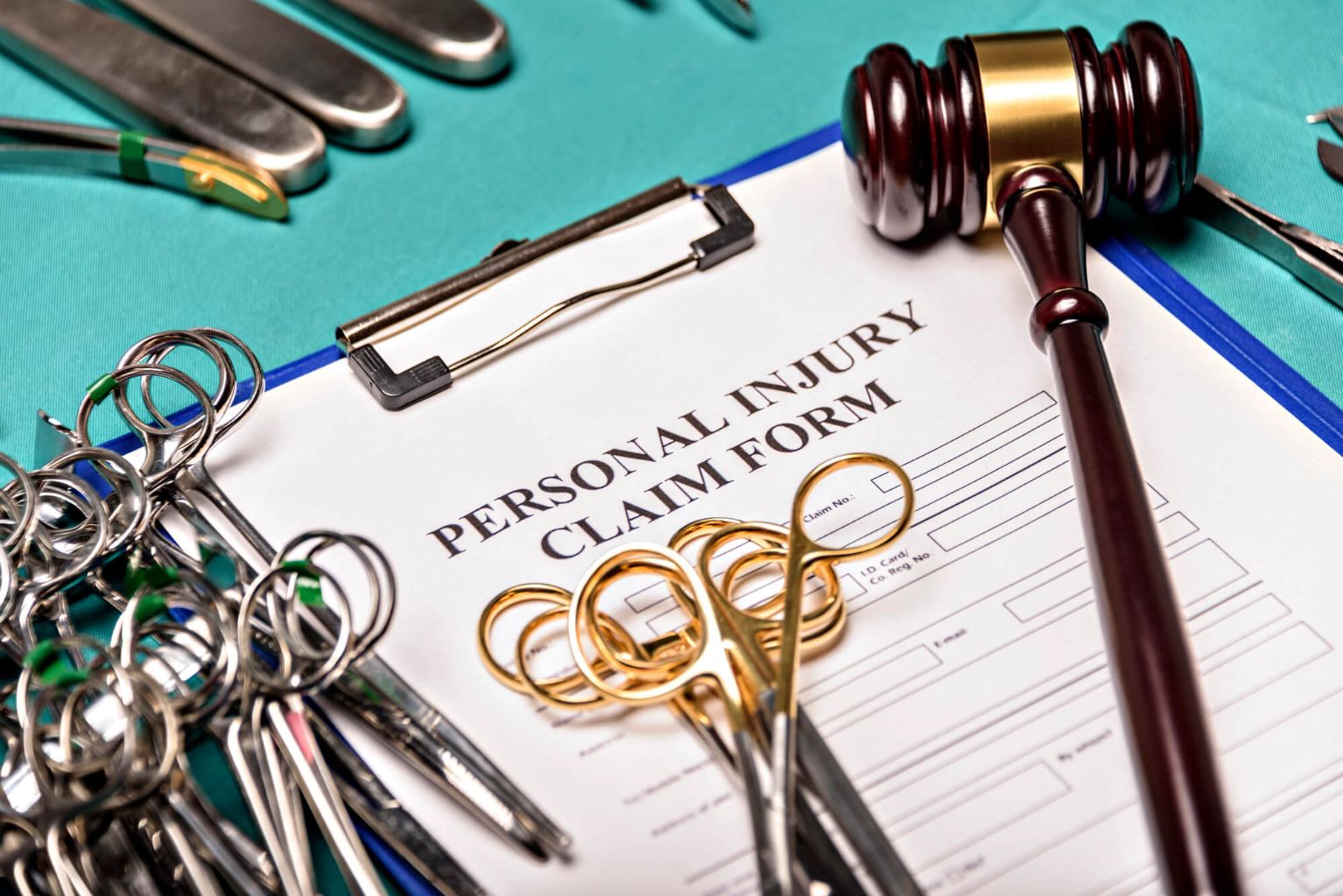 תמונת נושא של המאמר על עורך דין נזיקין בחיפה המציג טופס תביעת נזקי גוף על לוח כתיבה עם פטיש שופטים כהה ומכשירים כירורגיים רבים על בד ירוק המייצגים משפט רפואה ורשלנות